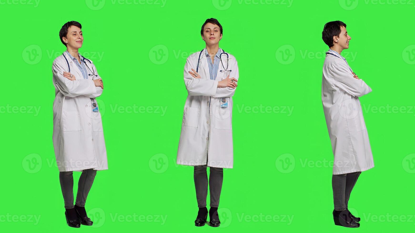 Portrait of successful physician standing with arms crossed against greenscreen backdrop, wearing a white coat and stethoscope. Doctor feeling confident with healthcare expertise. Camera A. photo