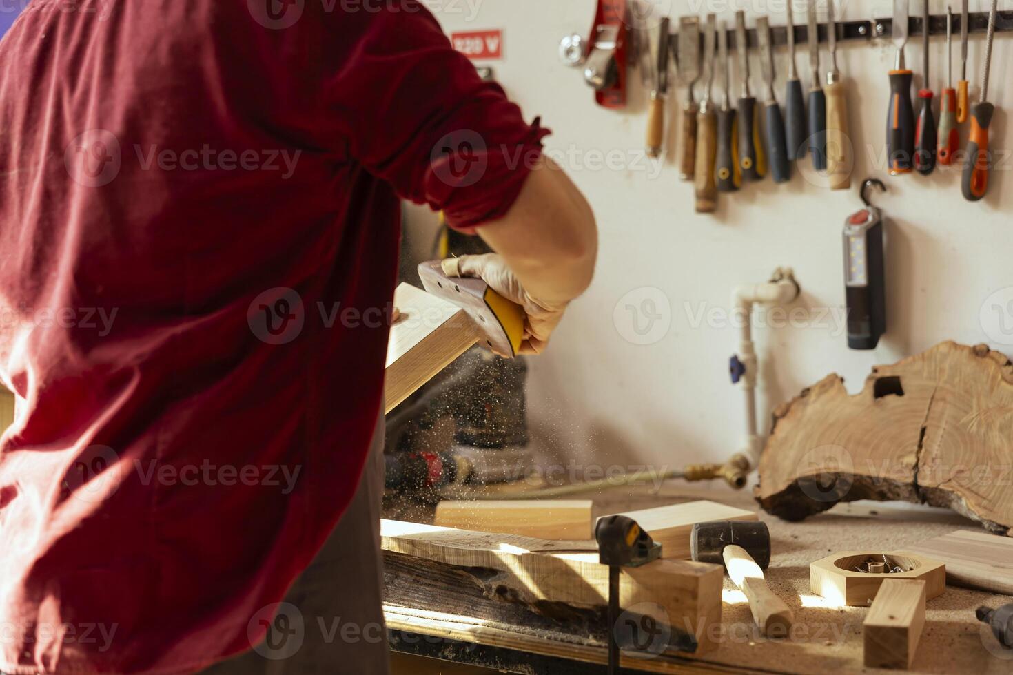 Woodworker using sandpaper to sander lumber block, making furniture in assembling shop with professional tools in background. Handyman polishing wood with abrasive material during renovation work photo
