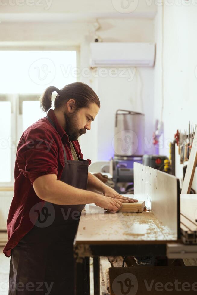 CNC machinist operating wood shaper in assembly shop, creating intricate designs with precision. Woodworking specialist uses spindle moulder to shape and mold timber pieces photo