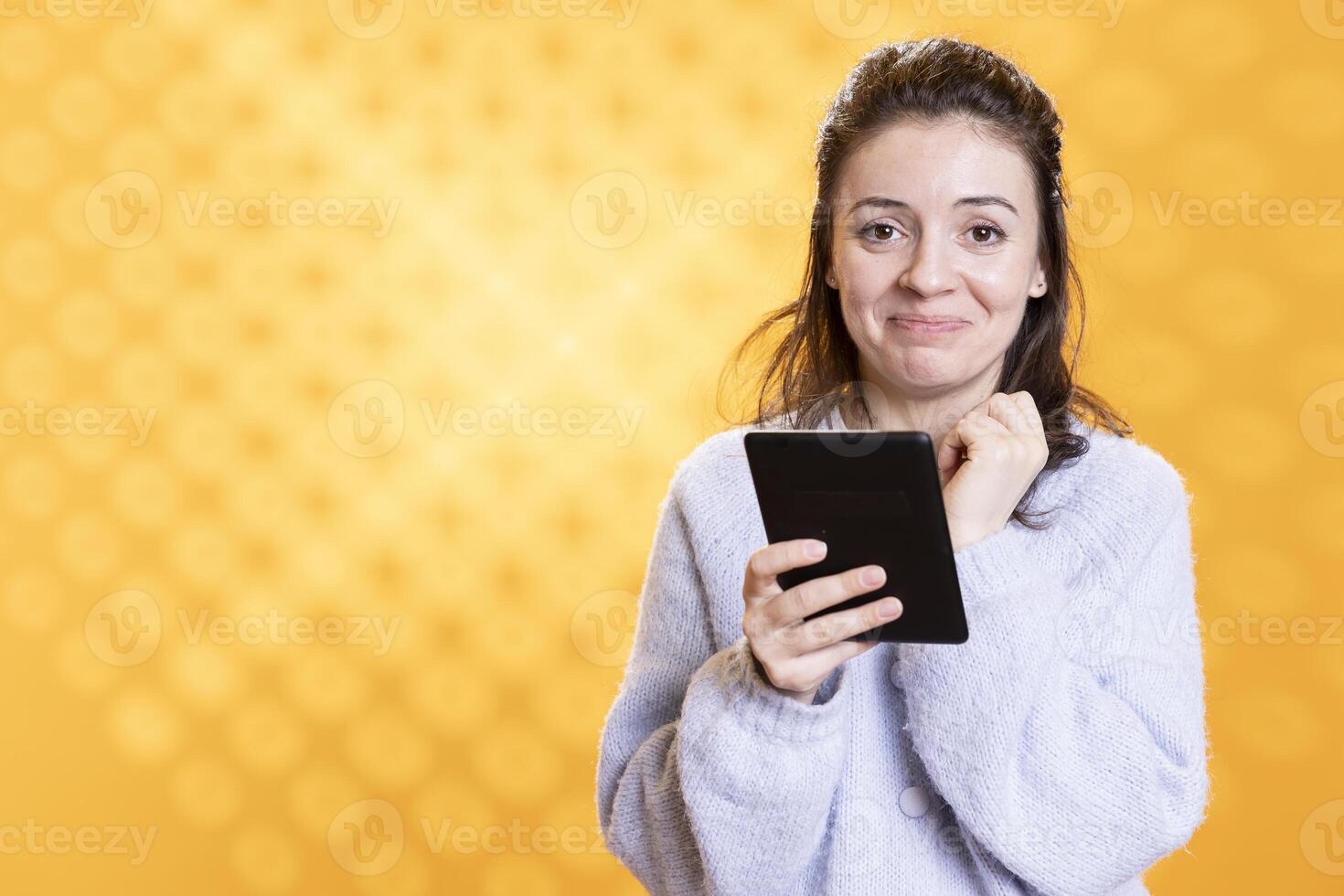 Emotional woman warmed by touching ebook on ereader, conveying joy of reading concept, studio background. Geek moved by warming digital novel on tablet screen, showing appreciation for literature photo