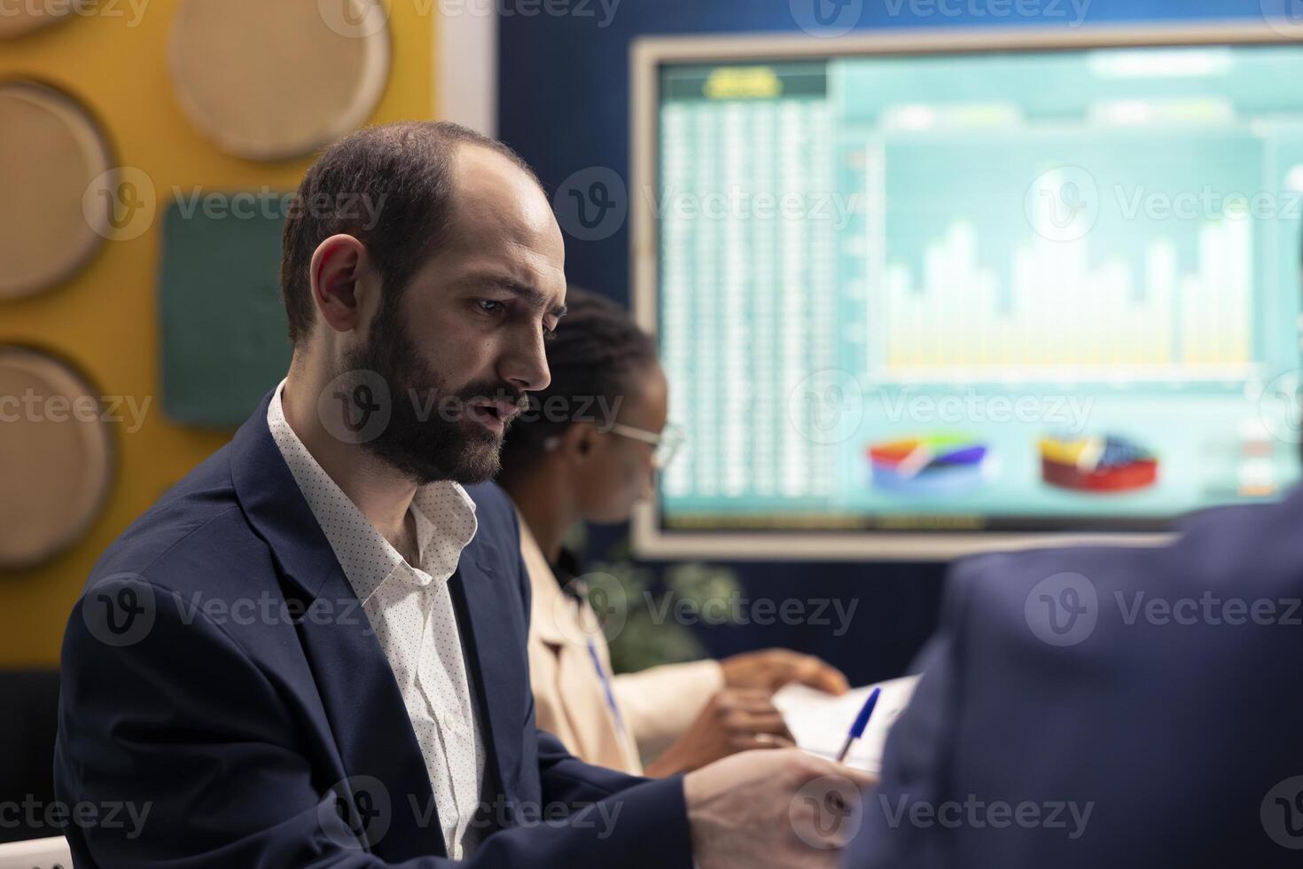 Business consultant evaluating corporate communications strategies, working to ensure goals and achievements for his staff members. Manager and employees collaborating on new project. photo