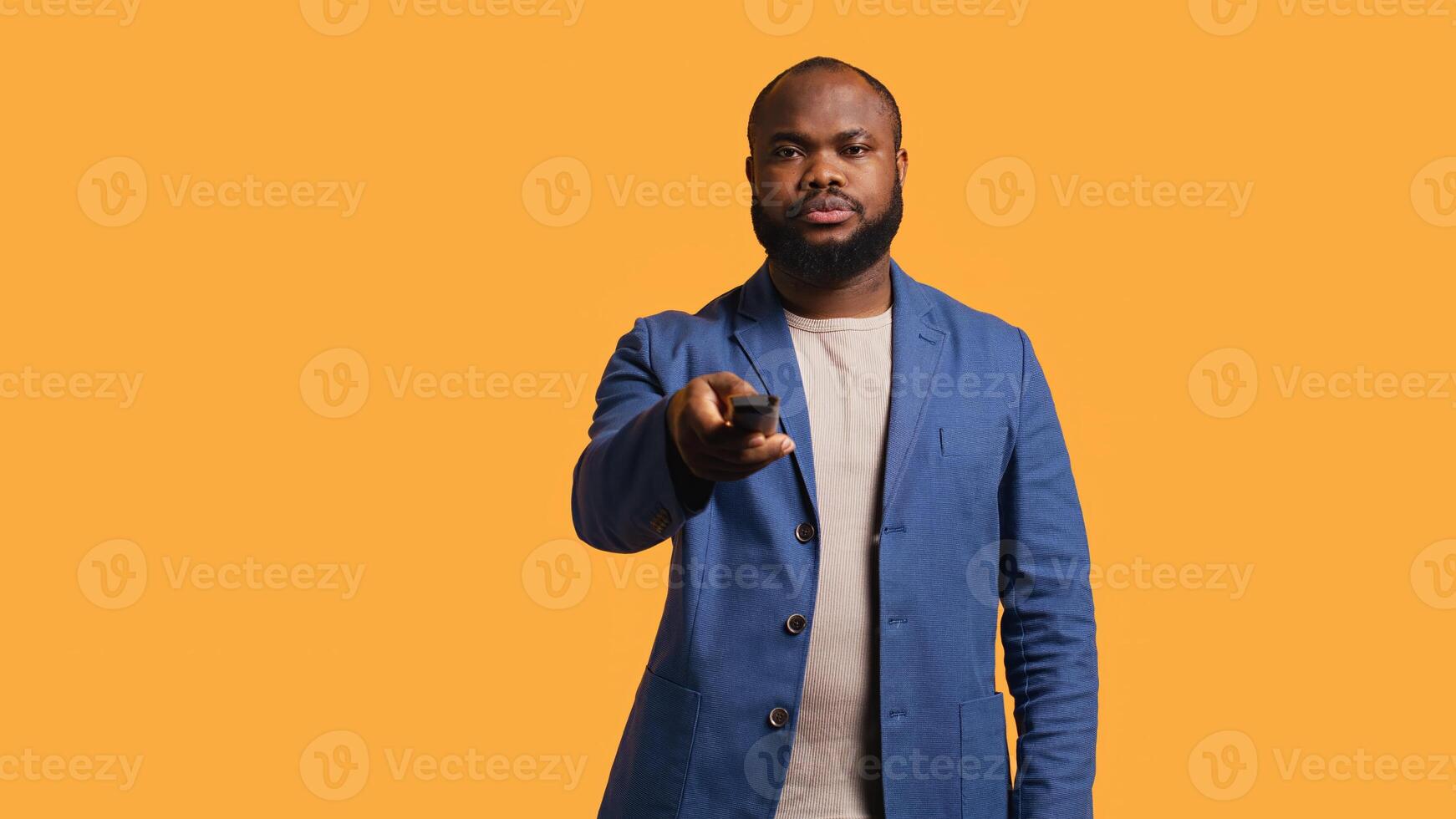 Man zapping through channels, watching news broadcast, isolated over studio background. African american person using remote control to select television station to enjoy, camera B photo
