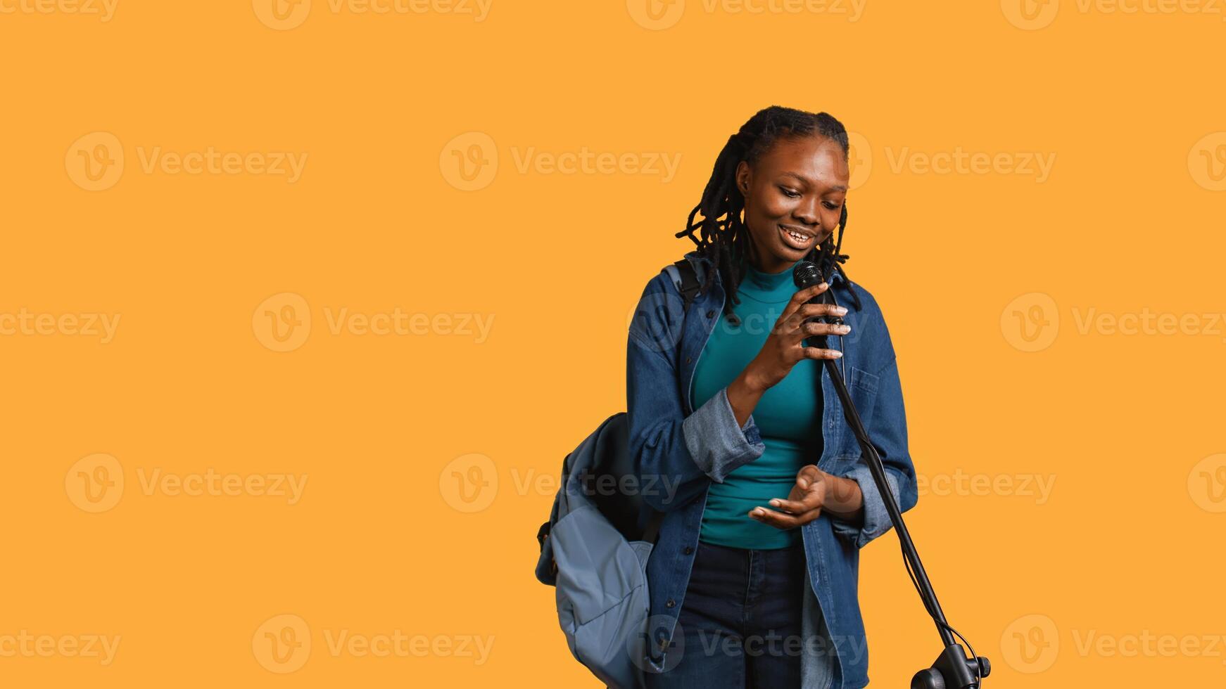 African american motivational speaker talking in microphone, addressing audience, holding speech, studio background. Inspiring woman using mic to present life lectures, camera B photo