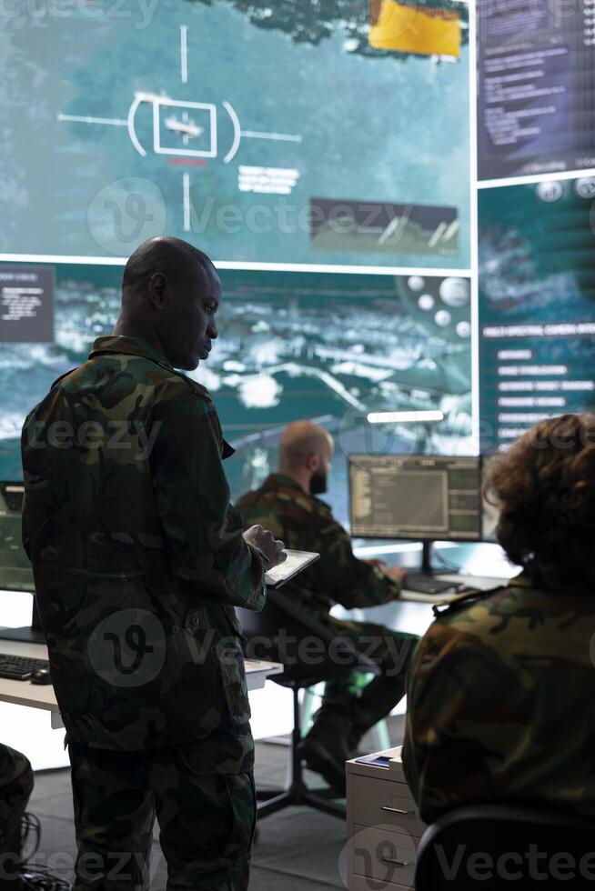 Special operations engineer examining surveillance CCTV footage to gather crucial information for a new mission, working on reconnaissance in general headquarters. Army conscripts in command post. photo