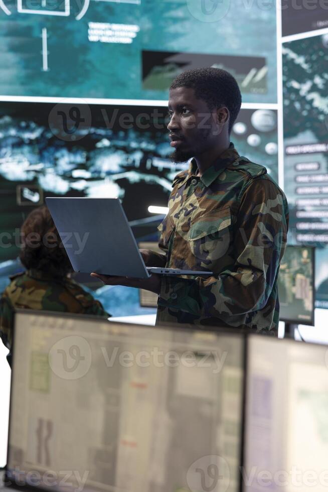 Intelligence analyst technician coordinating air support to provide assistance for ground troops, ensures correct functioning for future warfare operations. Works in reconnaissance control room. photo