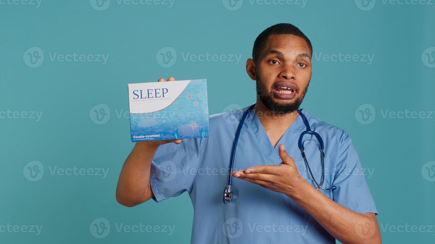 Portrait of african american medic holding sleep deprivation medicine package for insomniacs, studio background. Healthcare specialist recommending tablets for patients with insomnia, camera A photo