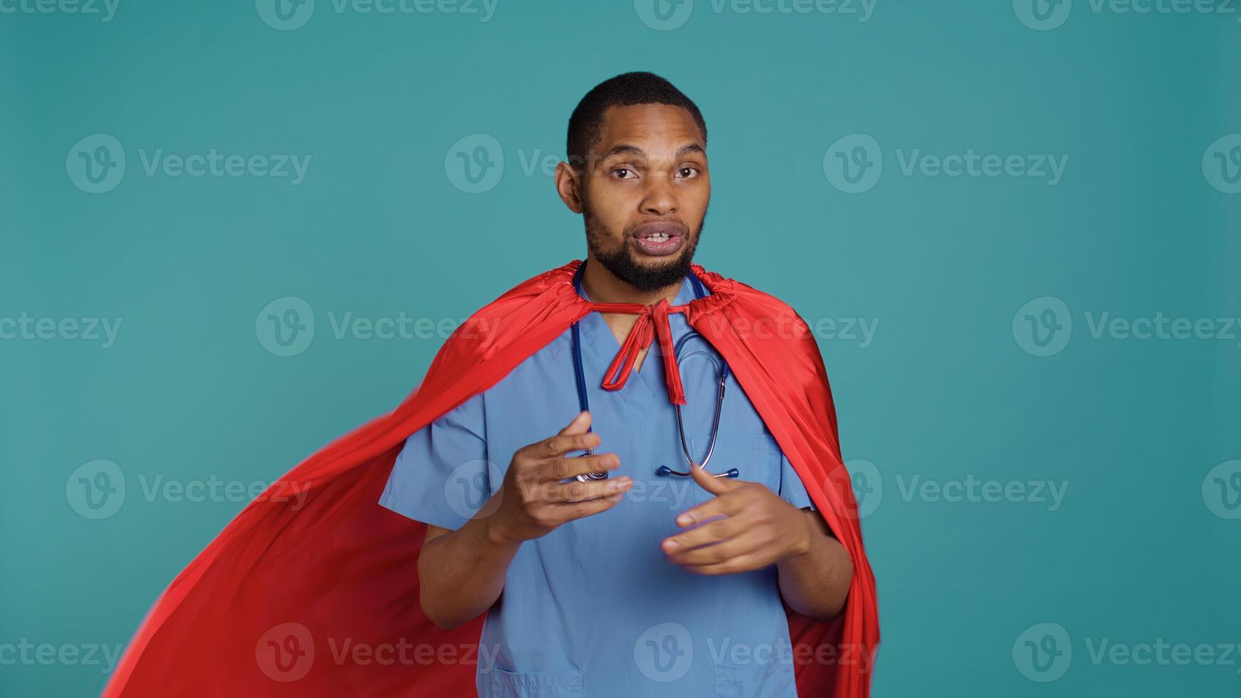 Male nurse portraying superhero showing courage and strength fighting diseases, studio backdrop. Portrait of african american doctor posing as hero in costume, holding empowering speech, camera B photo