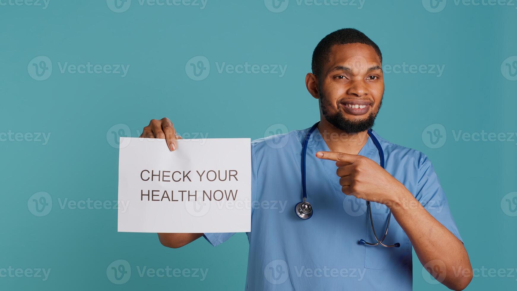 Portrait of upbeat nurse smiling, holding sign urging people to do doctor appointments, studio background. African american healthcare worker talks about importance of preventive healthcare, camera A photo