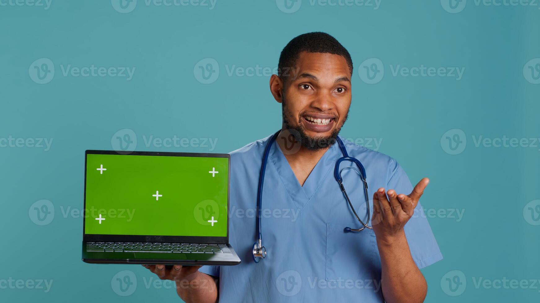 Portrait of practitioner in medical uniform showing instructions on isolated screen laptop. Healthcare professional doing presentation using mockup notebook, studio backdrop, camera A photo