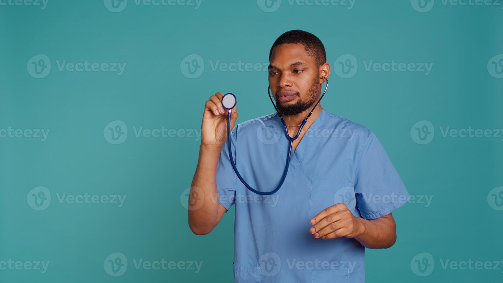 Male nurse using stethoscope on patient during medical exam, hearing heartbeat, isolated over studio background. Healthcare worker using clinic equipment to check for cardiac issues, camera B photo