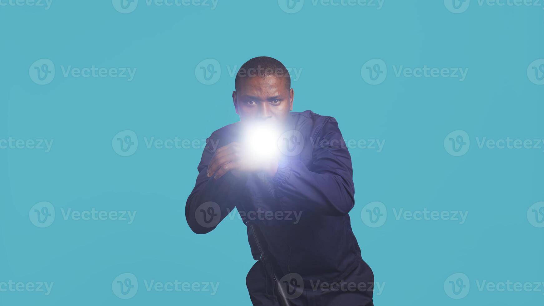 Portrait of security staff member tasked with evicting trespassers turns on flashlight. Patrolling agent maintains secure environment with lantern device, spotting people, studio background, camera B photo