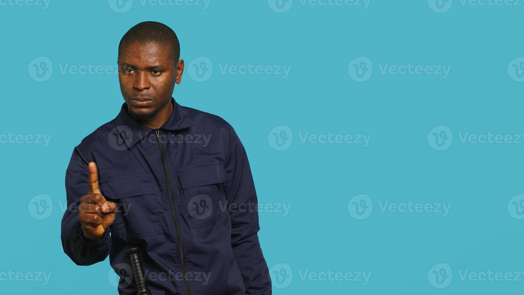 Security guard doing no gesturing with finger, prohibiting public access in restricted area. Portrait of stern bodyguard barring people from entering place, studio background, camera A photo