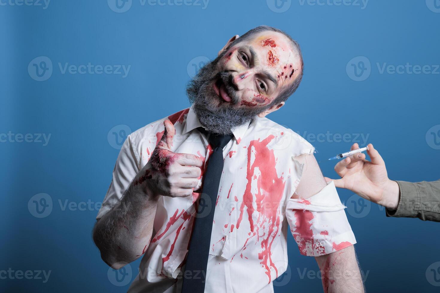 Man happy to take coronavirus vaccine shot showing thumbs up sign, obedient sheep conspiracy theory concept. Cheerful docile person manipulated to get covid injection, studio background photo