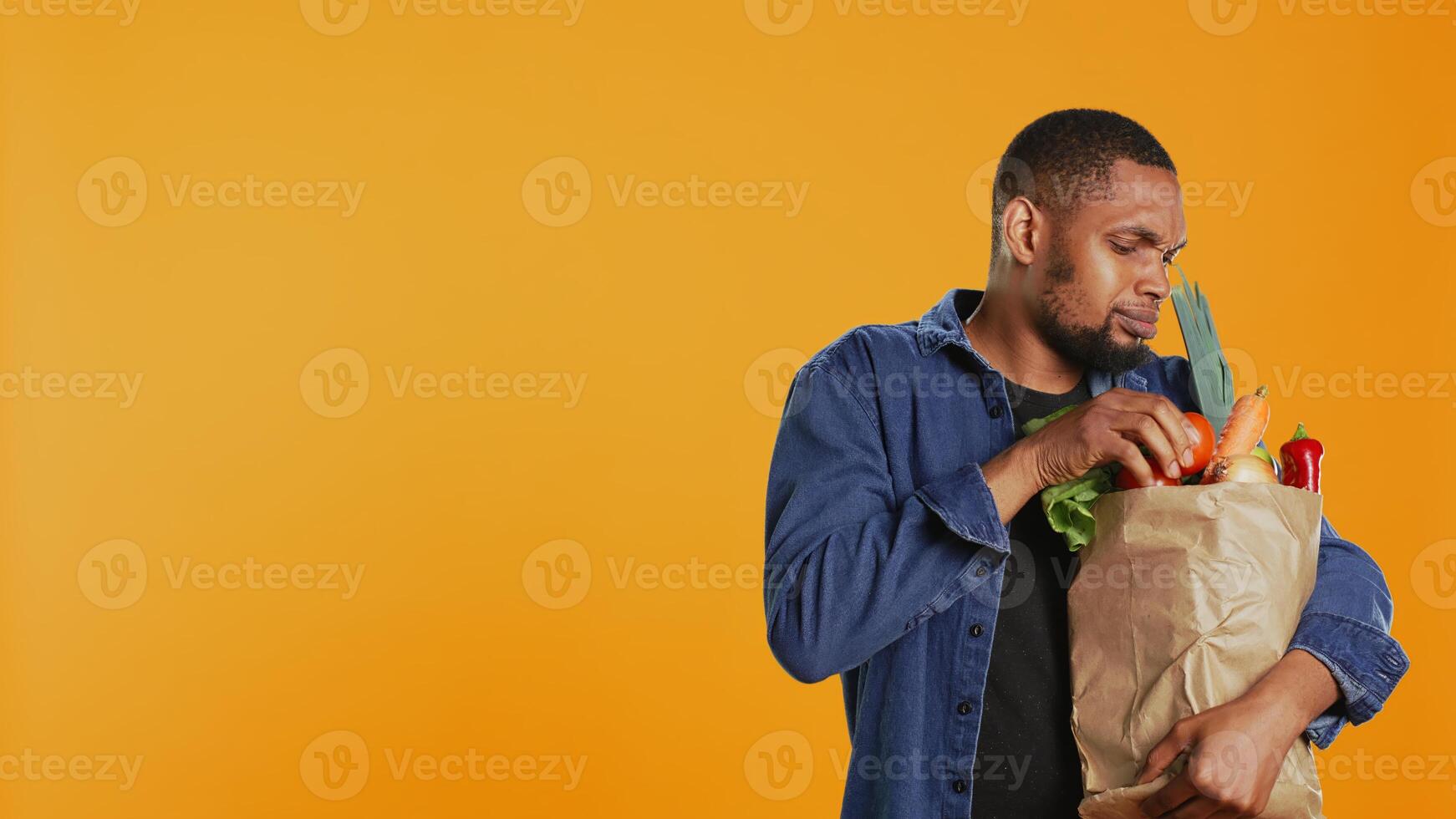 Person counting all his freshly harvested produce in a paper bag, making sure he bought important ingredients for his vegan meals. Male model eating only ethically sourced food. Camera B. photo