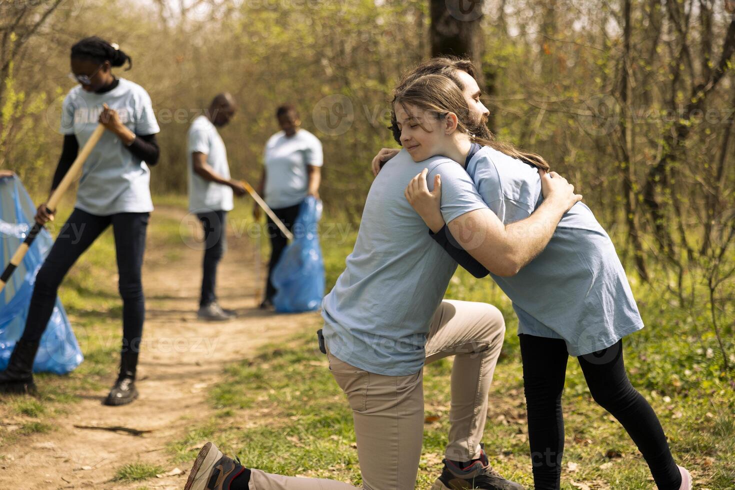 Sweet kid embracing her father after planting a tree together, feeling happy and satisfied with their collective voluntary work. Joyful dad and little child sharing a hug, successful unity. photo