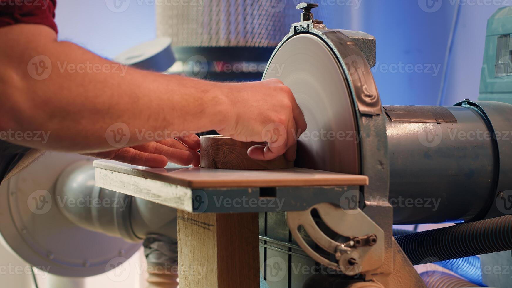 Manufacturer shaping wooden bowl on disc sander in assembling shop. Woodworking expert working in joinery, guiding wood against professional grinding machine rotating disc, camera A photo