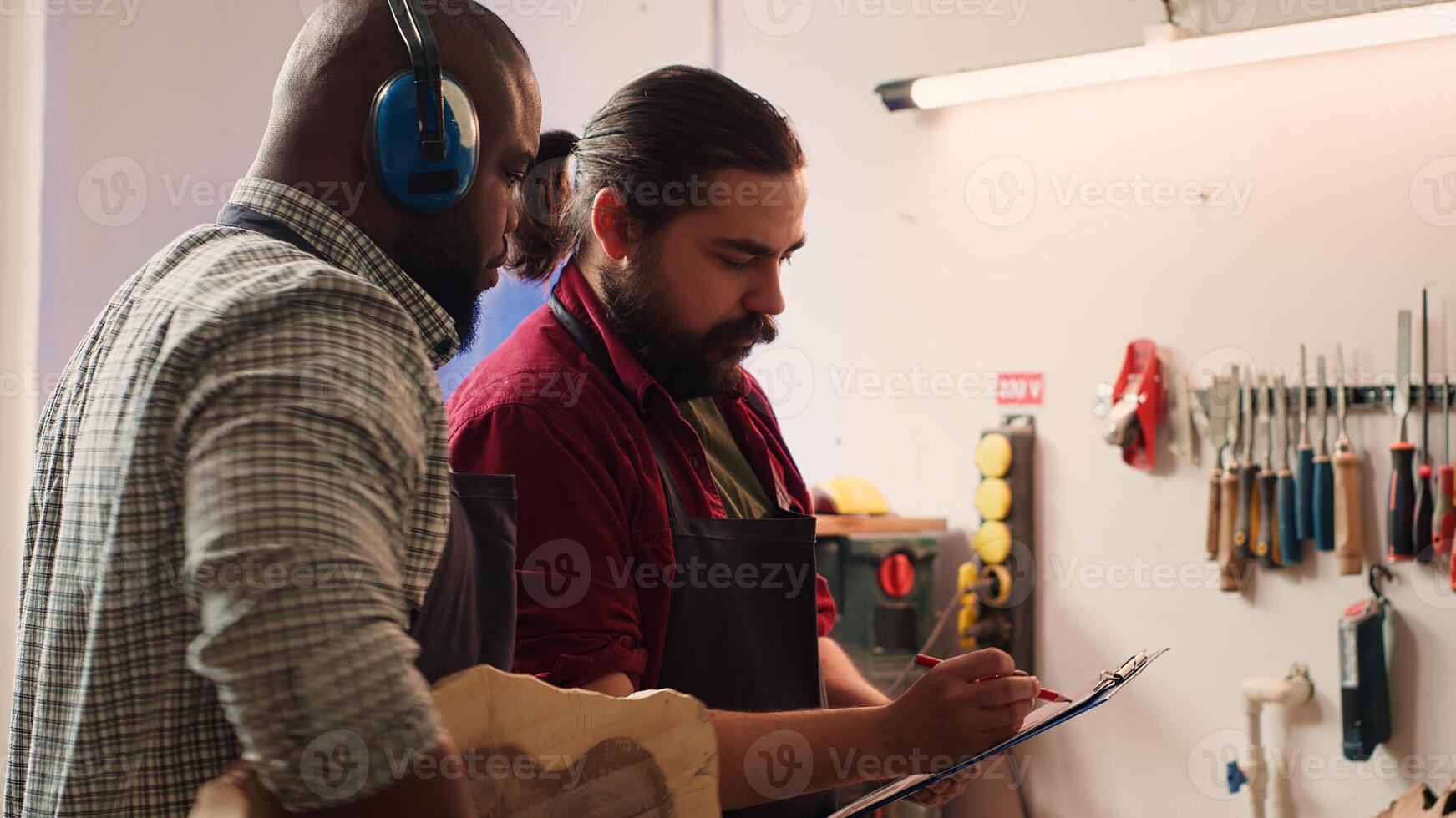 Carpenter and colleague looking over technical schematics, brainstorming ideas for wooden object. Master and apprentice analyzing blueprints to execute furniture assembling project, camera A photo