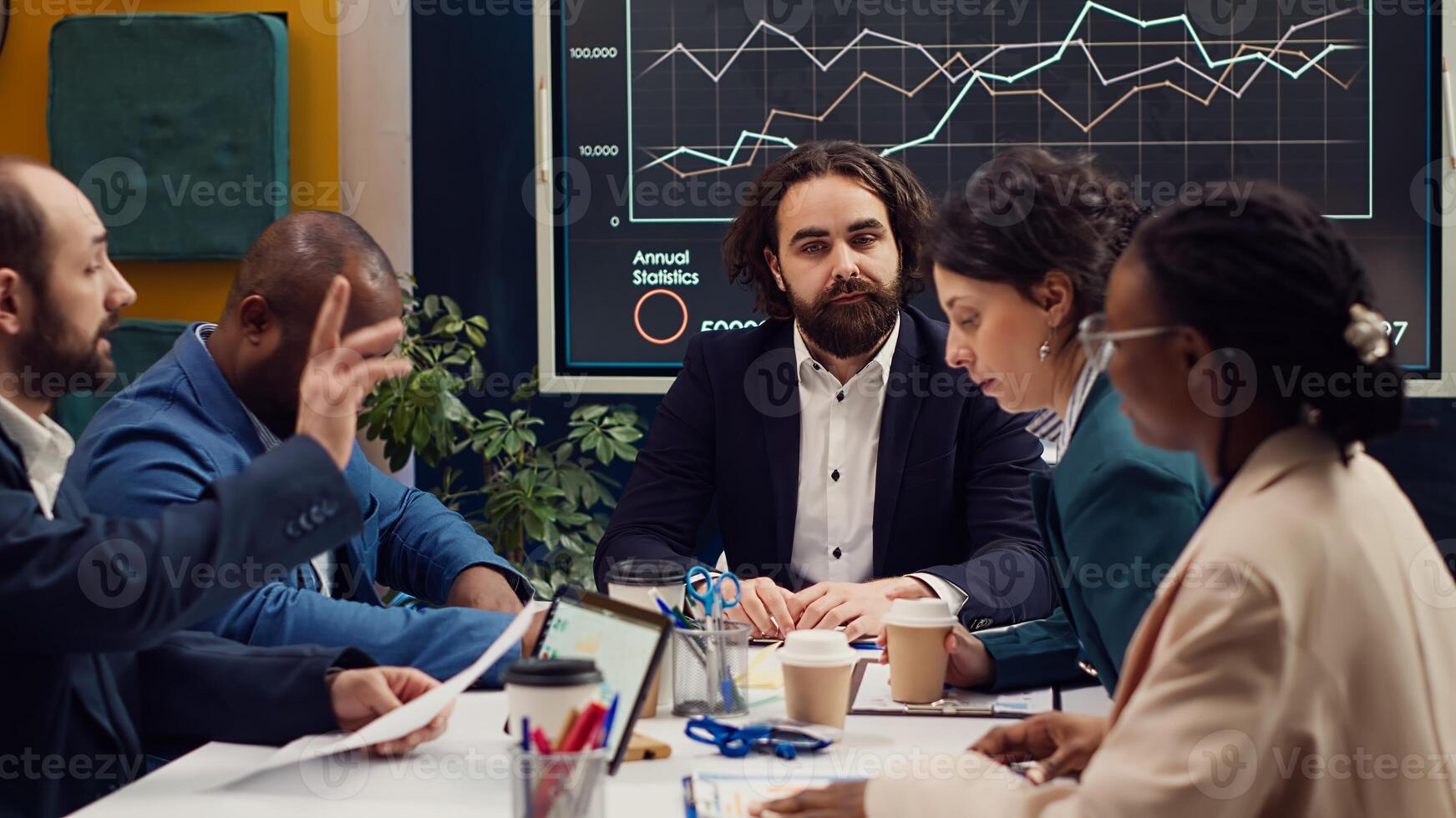 Business analysts meeting in a boardroom to discuss project stages and updates, gathering information from data reports and planning steps to coordinate with objectives. Employee engagement. Camera A. photo