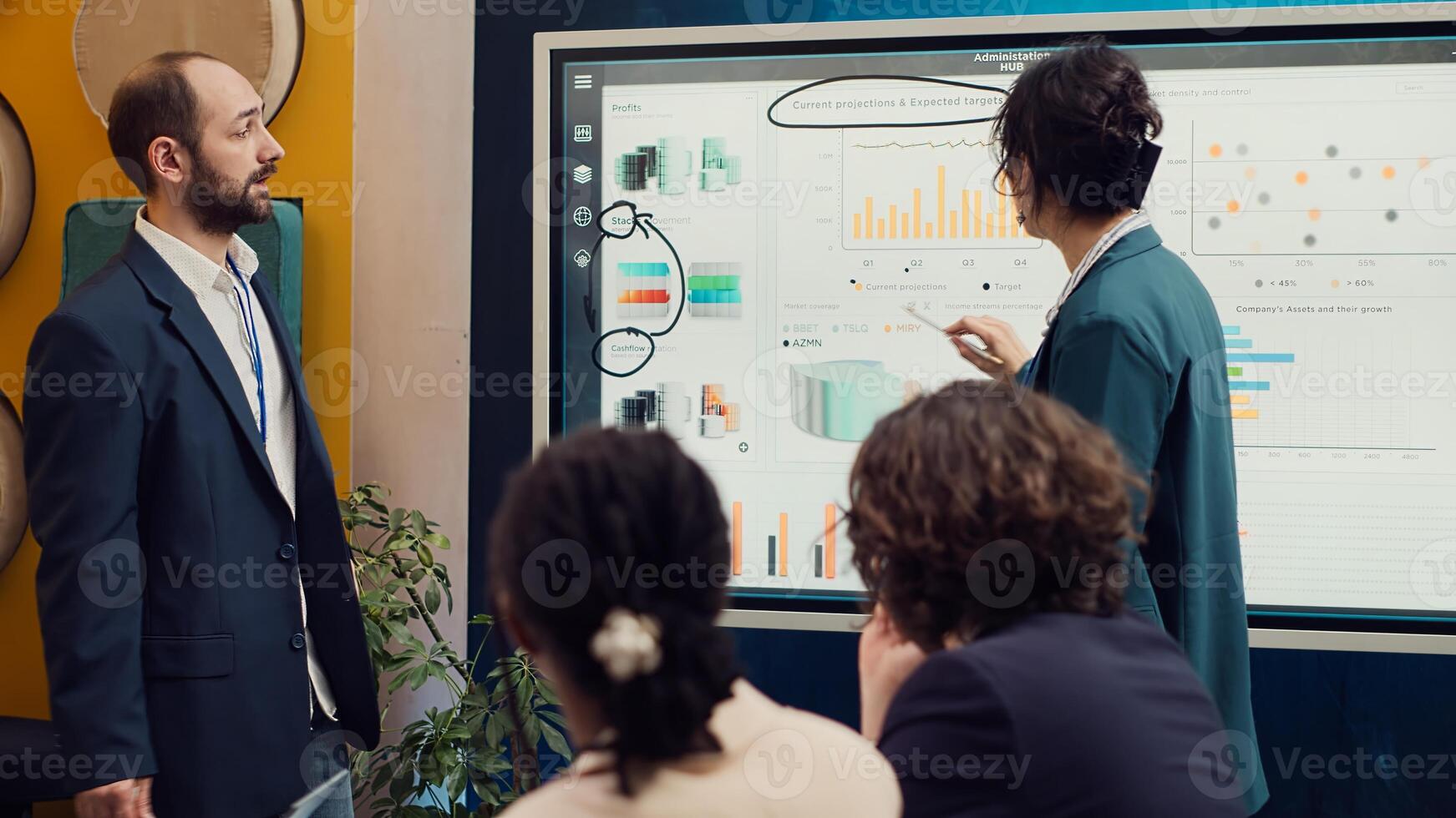 Project team reviewing monthly reports and data on interactive board, studying market trends and customer needs to ensure objectives fulfillment. Workers accomplish business goals. Camera A. photo