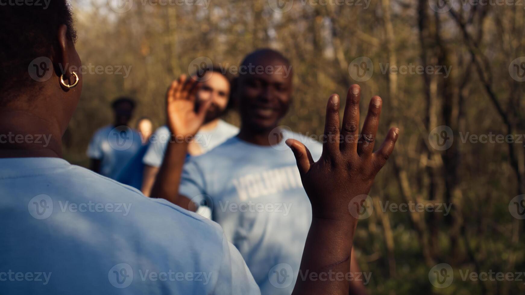 Team leader sharing a high five with her volunteers members after litter cleanup success, praising each other and feeling satisfied with nature preservation. Collecting rubbish and cleaning. Camera B. photo