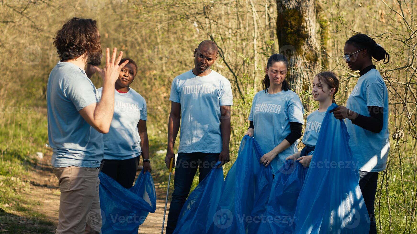 Team of activists picking up plastic waste to recycle and collect rubbish, cleaning the forest natural environment for conservation. People doing voluntary work to save the planet. Camera A. photo