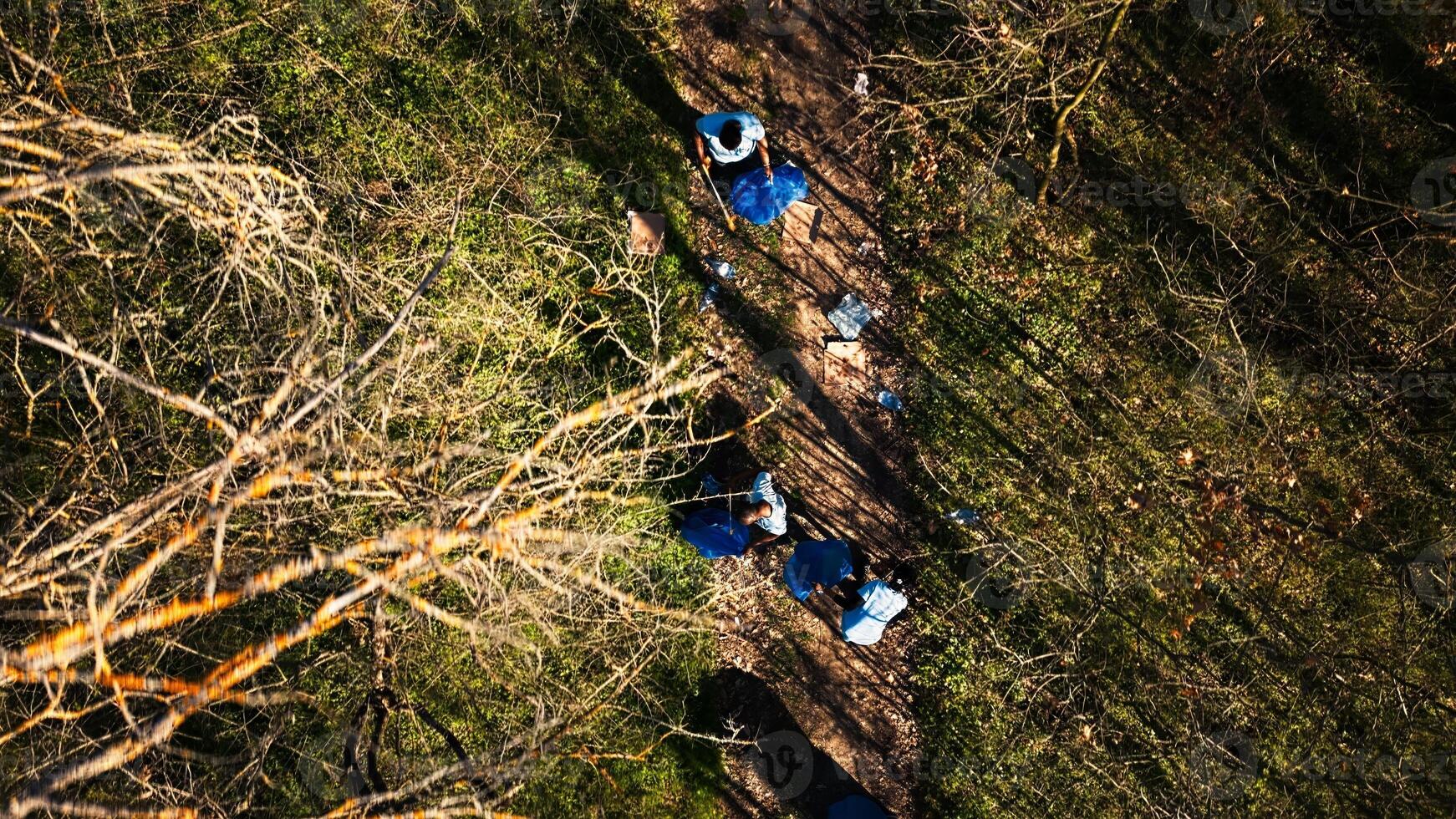 Aerial view of campaigners joining forces to recycle and tidy up garbage in a forest in order to safeguard the ecosystem. Individuals having ecologic conservation principles, eco friendly. photo