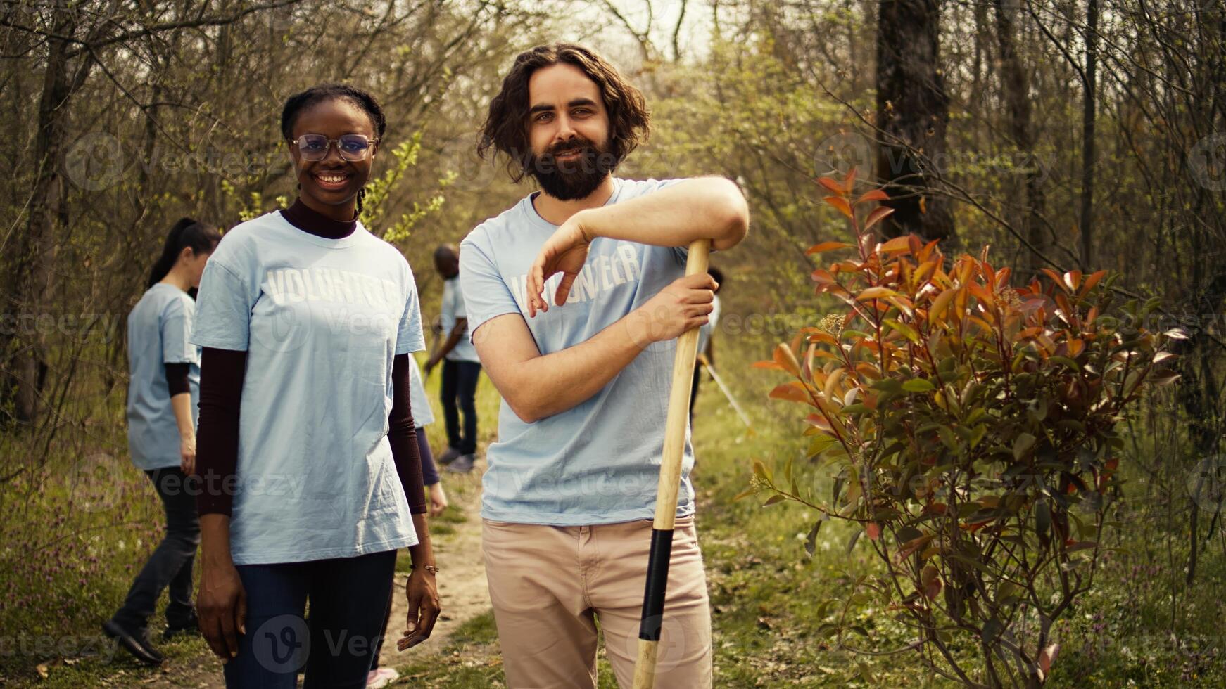 Portrait of two activists clearing up the forest surroundings by collecting garbage, growing new trees and picking up trash. Eco friendly enthusiasts preserving environments and wildlife. Camera B. photo