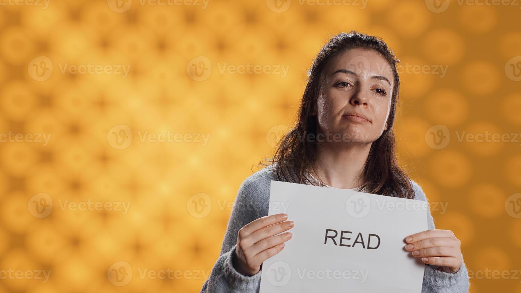 Woman holding message in hands urging people to read more, talking about importance of lecture, isolated over studio background. Bookworm promoting literacy concept, camera A photo