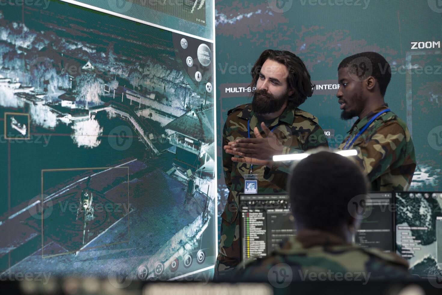 Professional IT specialists collect information for field operations, using federal satellite imagery on CCTV system in military base. Troopers checks important real time data on a big screen. photo