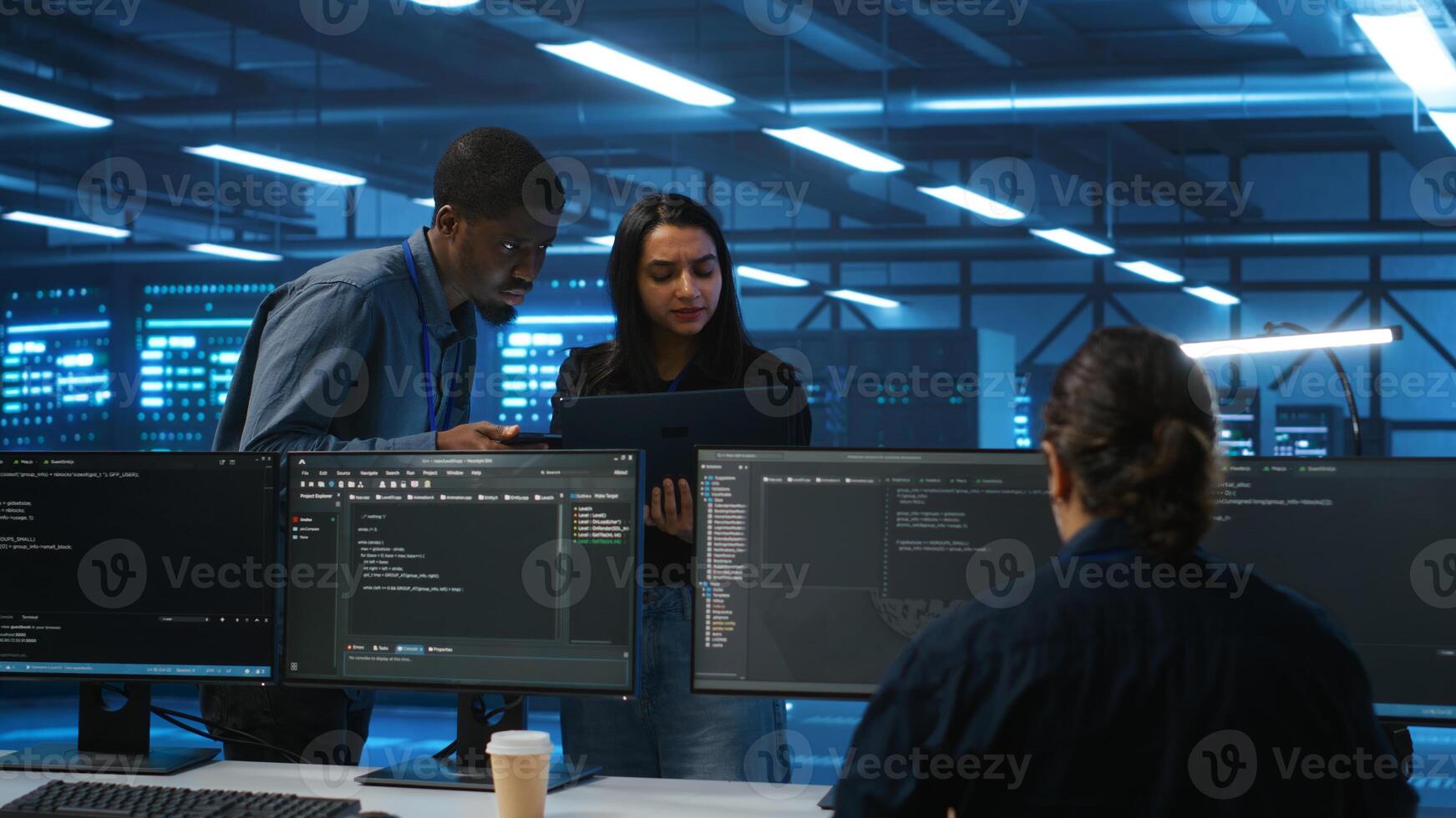 Manager overseeing server room using laptop to do hardware troubleshooting, talking with multiracial employees. Supervisor doing inspection in data center, receiving performance assessment from worker photo