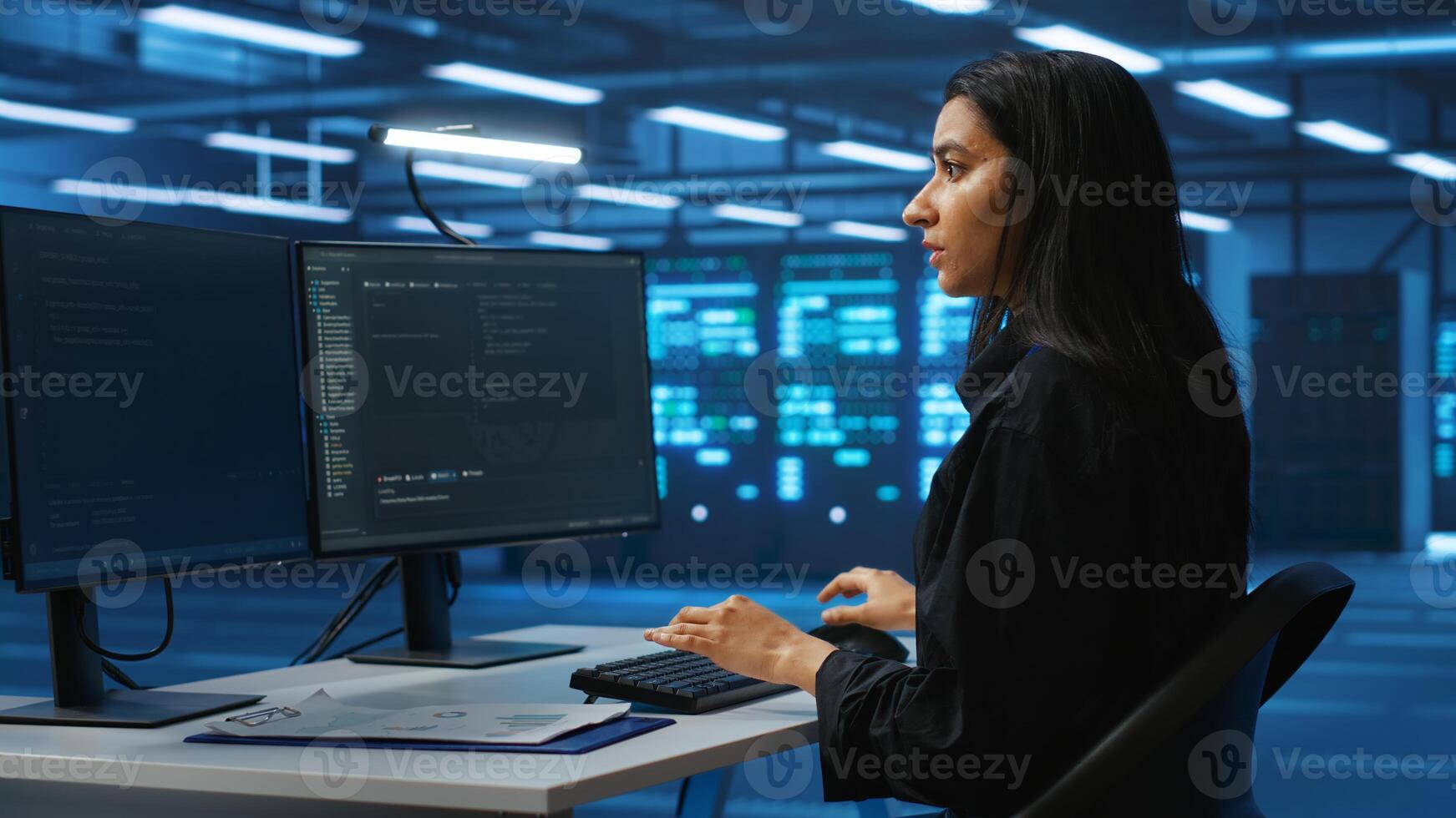 Technician working in high tech server room, analyzing data on multiple monitors, ensuring seamless data flow. Woman examining racks in data center, ensuring system integrity and security photo