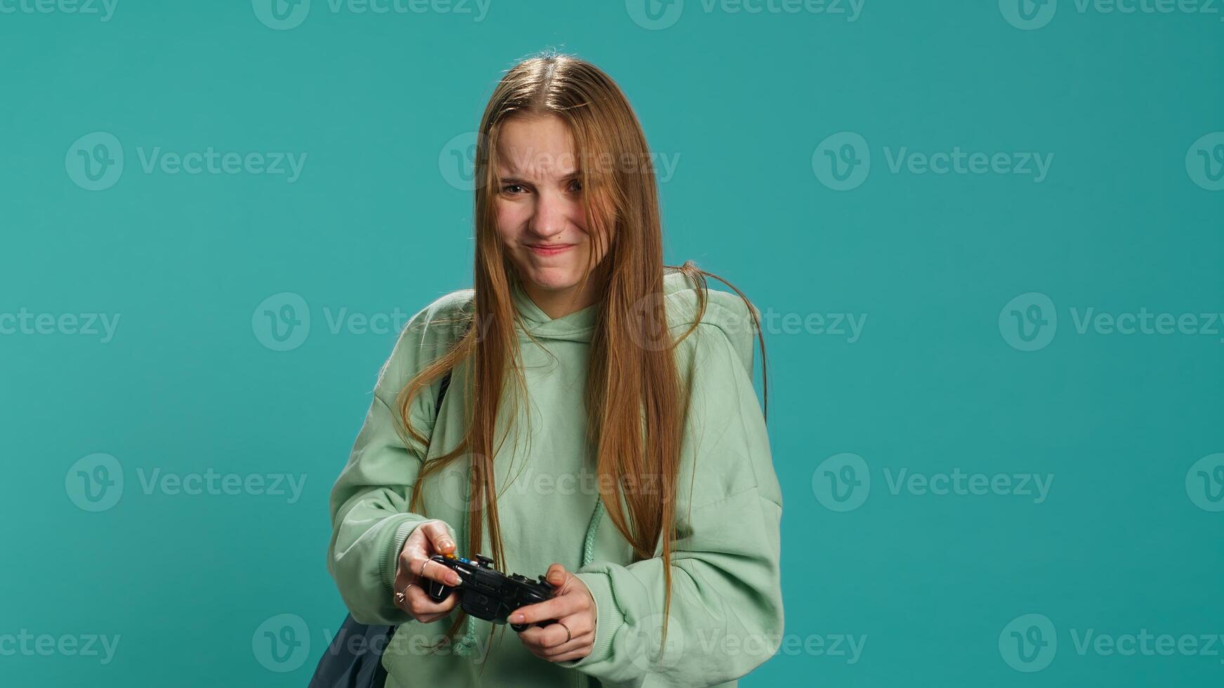 Young girl spamming controller buttons, disappointed after receiving game over screen. Woman upset after losing videogame, playing with gamepad, studio background, camera A photo
