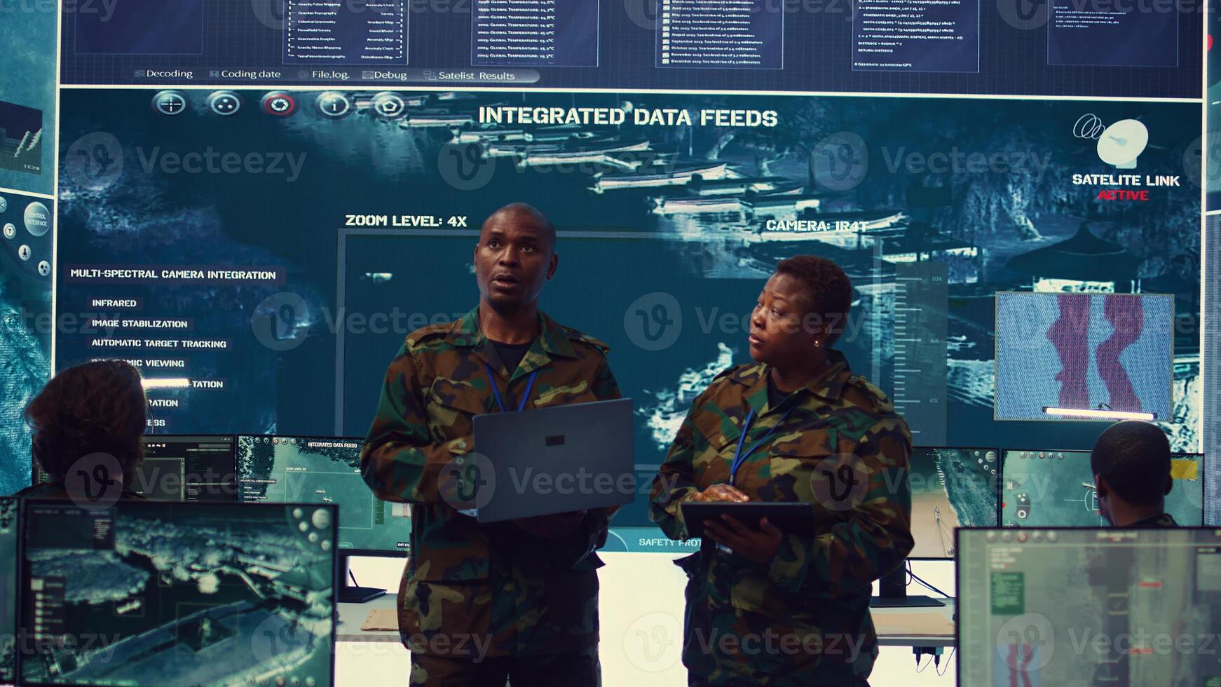 Sergeant major and female soldier checking real time field data in command post monitoring room, examining missions and operations. Team of troops interprets satellite imagery. Camera B. photo