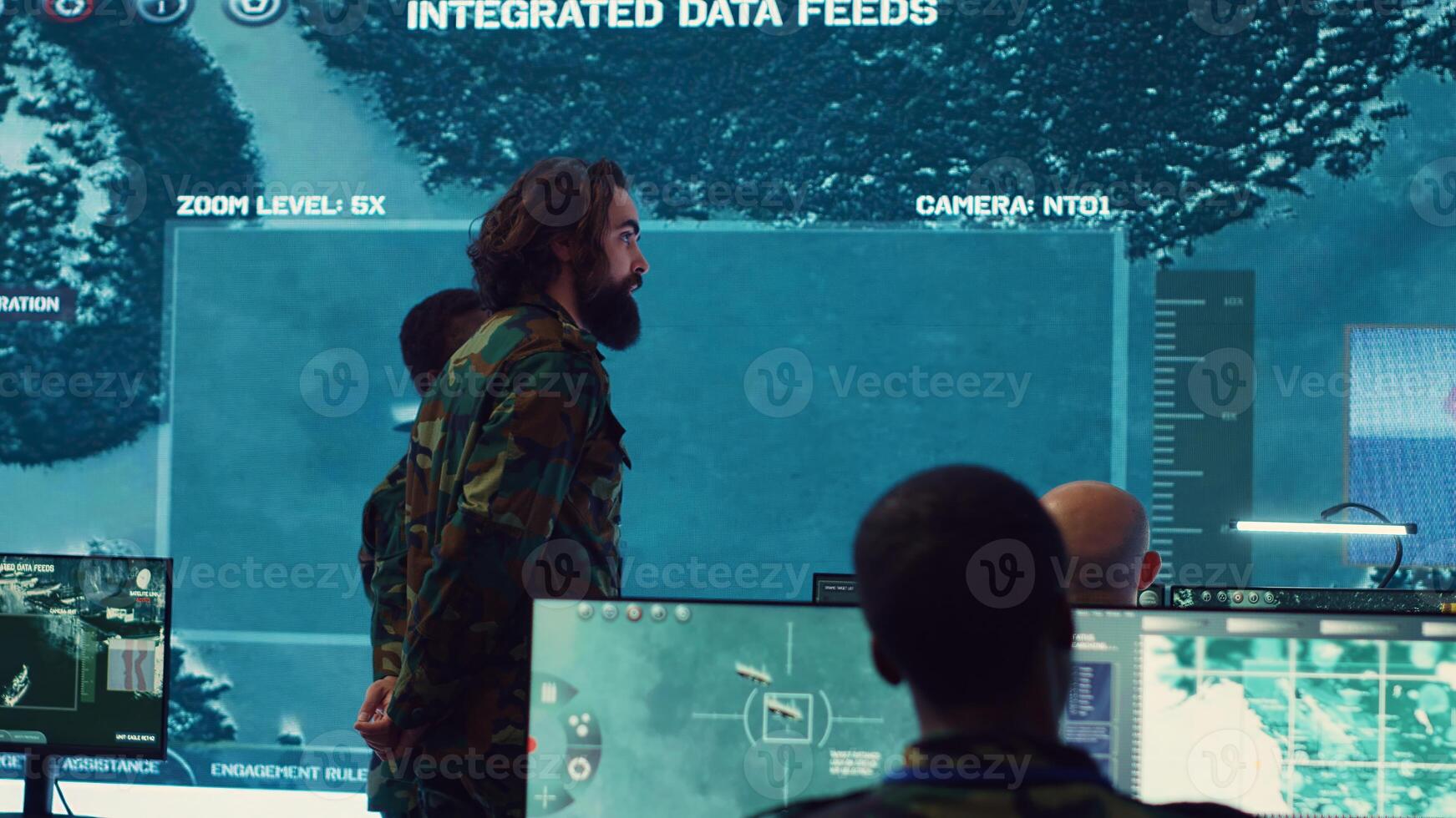 Military surveillance officers talking next to a big screen in general headquarters for cyber operations, control and monitoring to manage national security and army communications. Camera A. photo