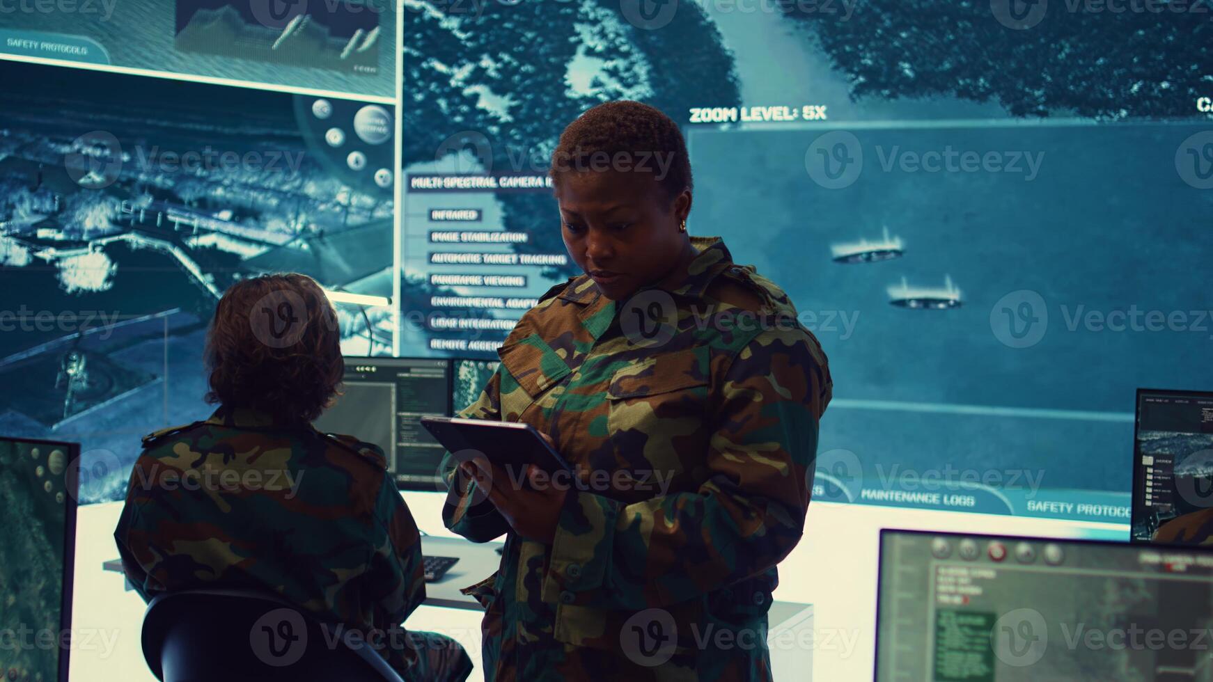 Female military officer supervising radar surveillance footage to input and process tactical data on a big screen. Woman uses global reconnaissance in creating battlefield maps. Camera B. photo