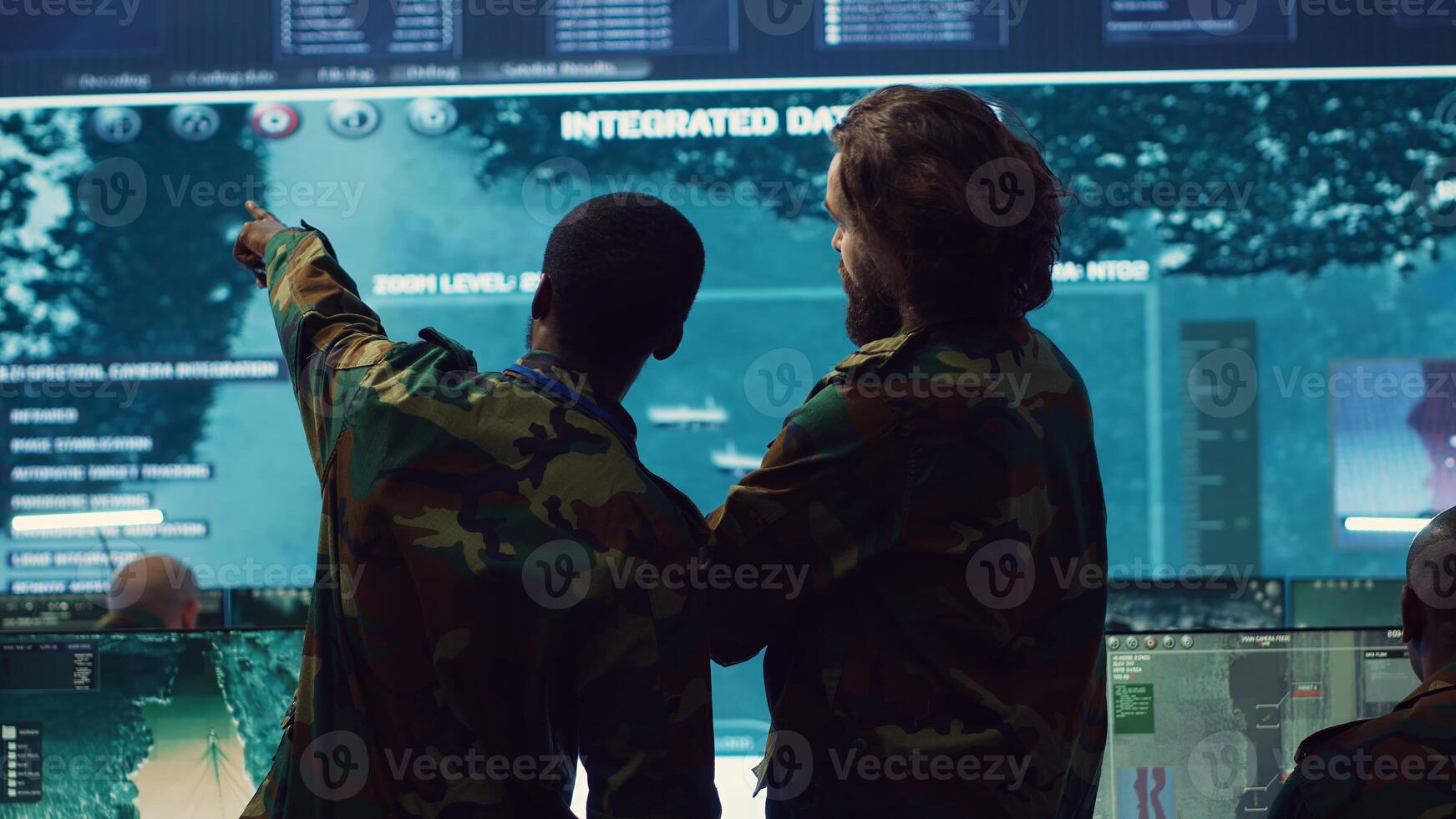 Diverse team of military personnel examining gathered information from CCTV satellite footage, transmitting crucial data to field troops. Army officers work on defense in command center. Camera A. photo