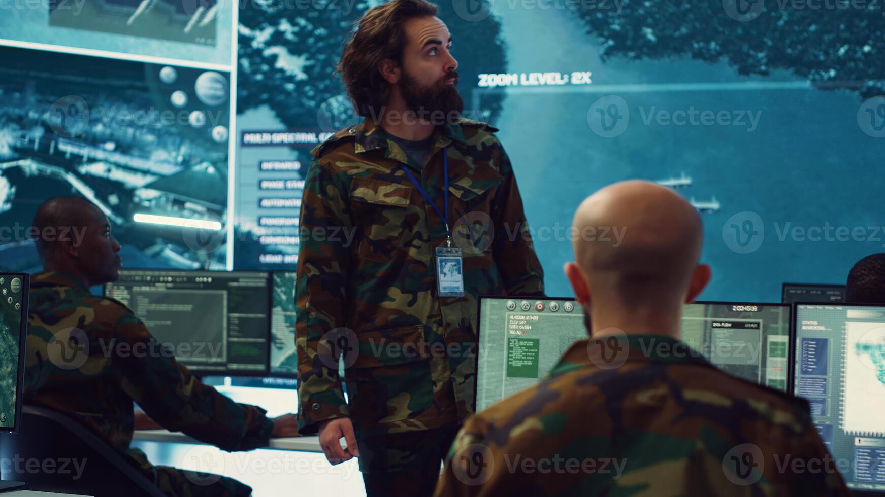 Staff sergeant providing mission files to brief his operational crew, working on gathering intelligence from surveillance systems. Prepares for various combat scenarios and outcomes. Camera A. photo