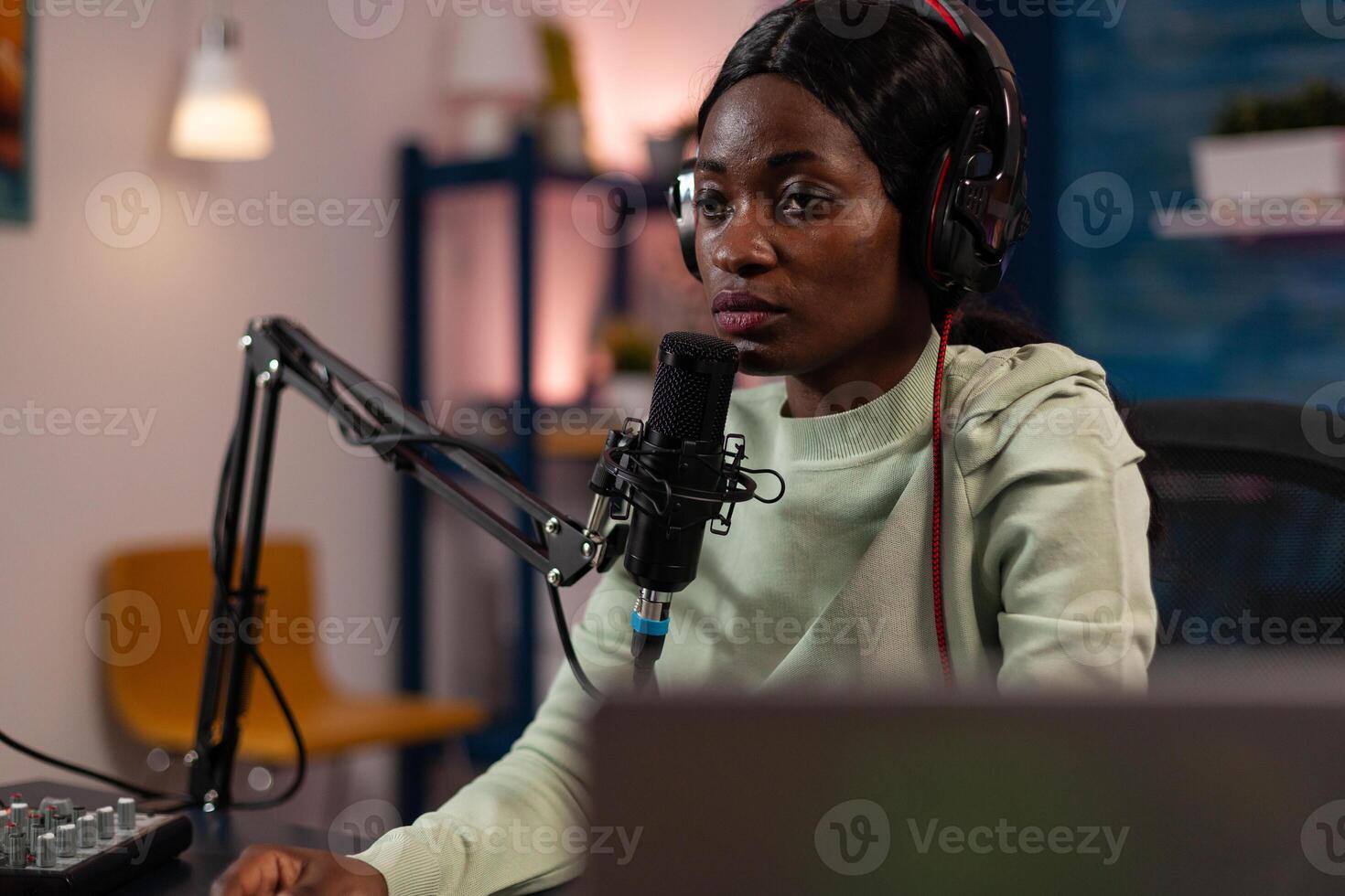 Social media content creator woman wearing headset talking with subscribers using professional production microphone hosting on air talk in living room. Vlogger person recording entertainment podcast photo