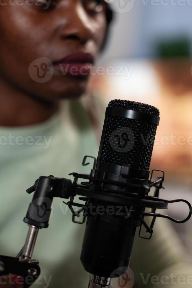 Closeup of social media content creator talking into vlogging microphone with subscribers answering question while recording entertainment podcast. Woman vlogger hosting on air talk photo