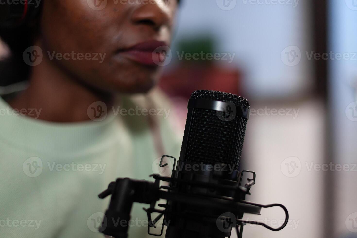 Closeup of african american vlogger woman talking into professional microphone with subscribers answering question while filming podcast. Social media content creator hosting on air talk photo