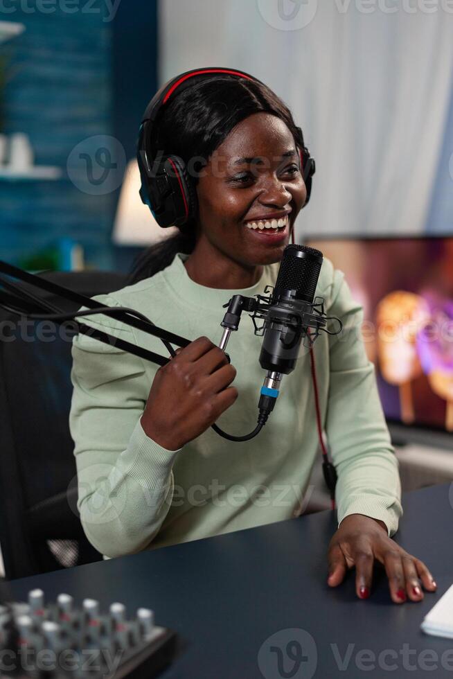 Social media influencer filming vlog talking into microphone answering subscribers questions. Content creator woman recording on air talk show using vlogging production equipment in living room photo