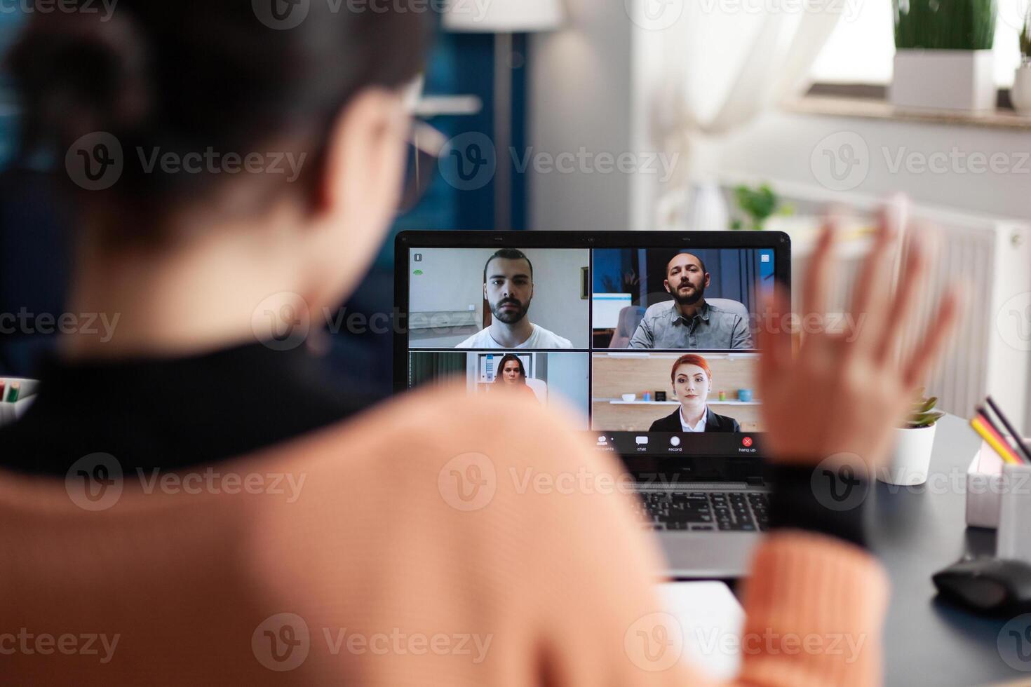 Student in a group videocall on laptop. Freelancer working from home office meeting colleagues online. Colleague waving at screen in webcam team conference. Remote briefing conversation. photo