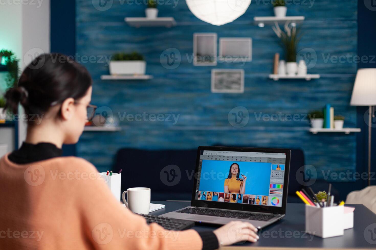 Graphic designer retouching photos on laptop. Student creative artist editing photos working from home office. Graphic designer using editing software to retouch photographs.
