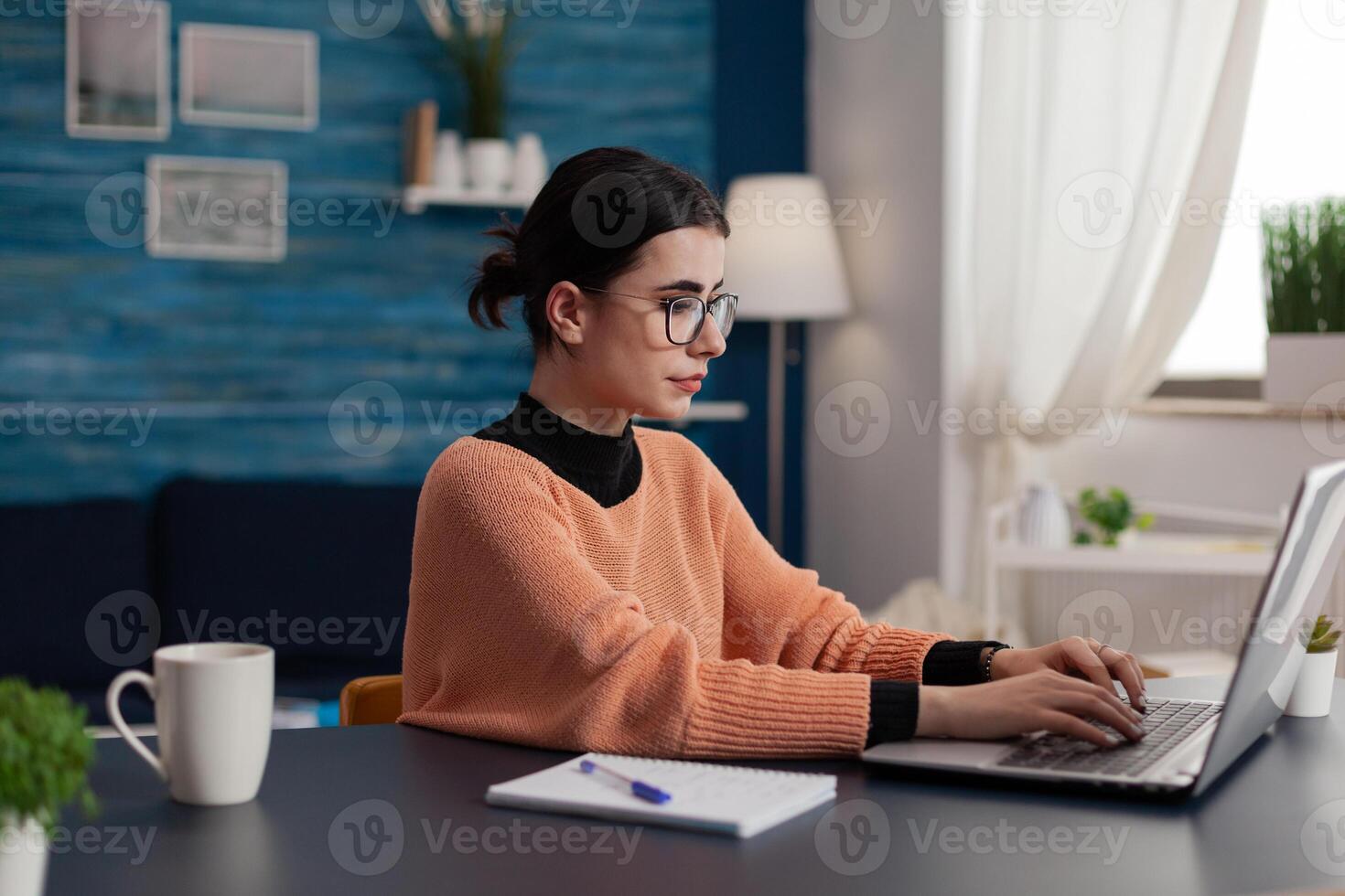 Student with glasses typing on laptop sitting at home desk. College girl with notebook studying remote looking at screen. Freelancer working from home sending email. Programmer browsing the internet. photo