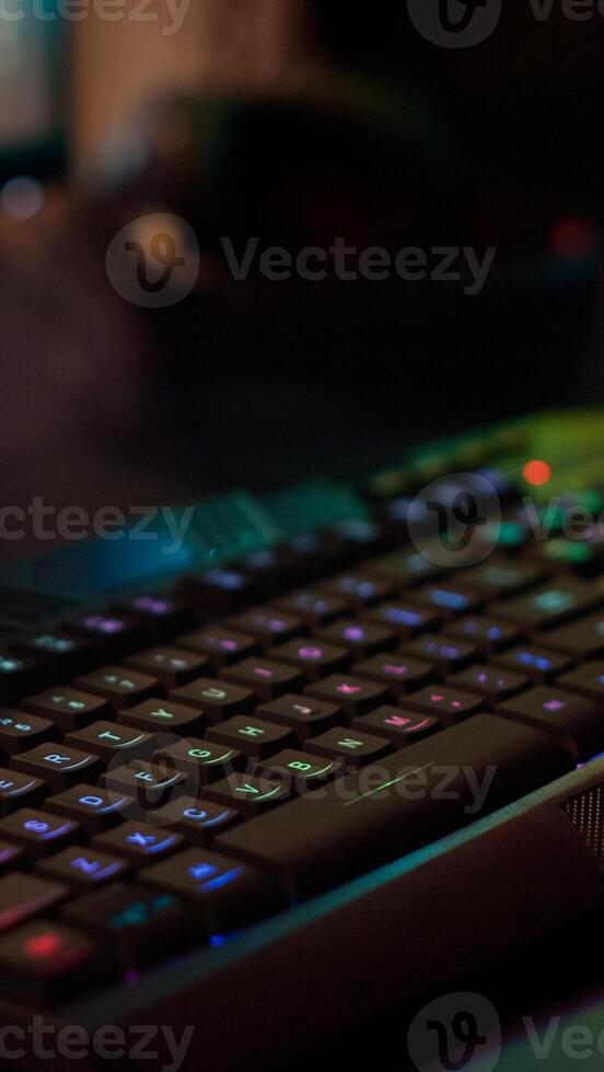 Close up of professional keyboard with RGB lighting prepared for streaming online tournament, display with first person shooter playing on it. Gaming studio of esport game with powerful computer photo