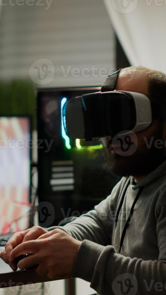 Videogame player with VR headset raising hands after winning space shooter competition. Professional pro gamer playing online games with new graphics on powerful computer from gaming room photo