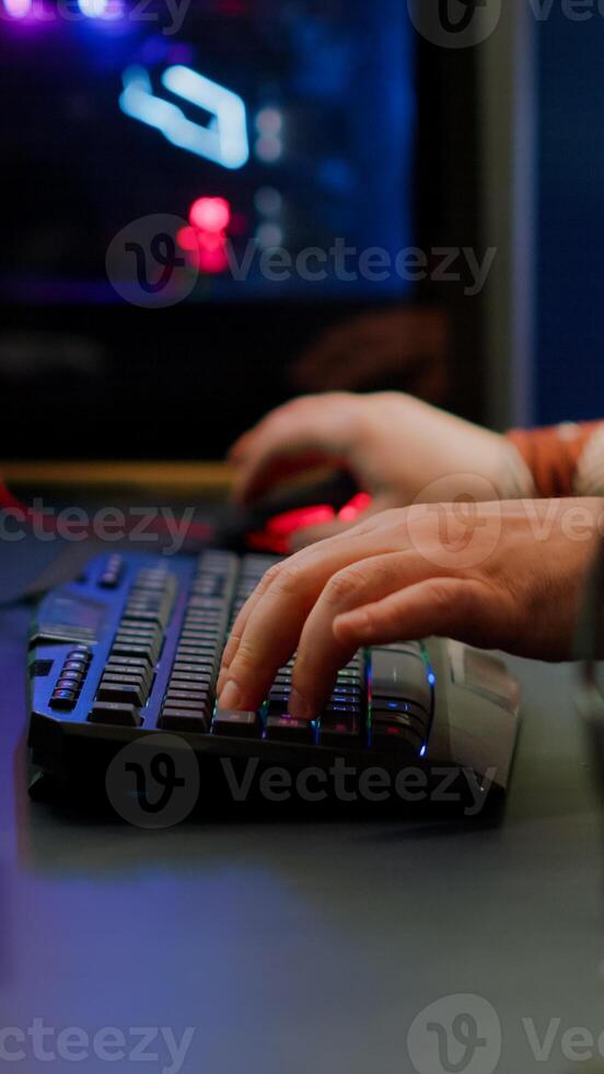 Close up of streamer typing at RGB keyboard playing space shooter videogame. Pro cyber man using mixer sound in gaming home studio for online esports competition on professional powerful computer photo