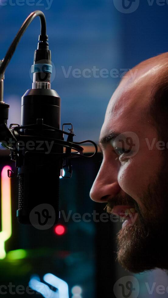 Pro streamer sitting on gaming chair talking with players using professional micorphone playing space shooter game during online tournament. Cyber man discussing on streaming chat photo