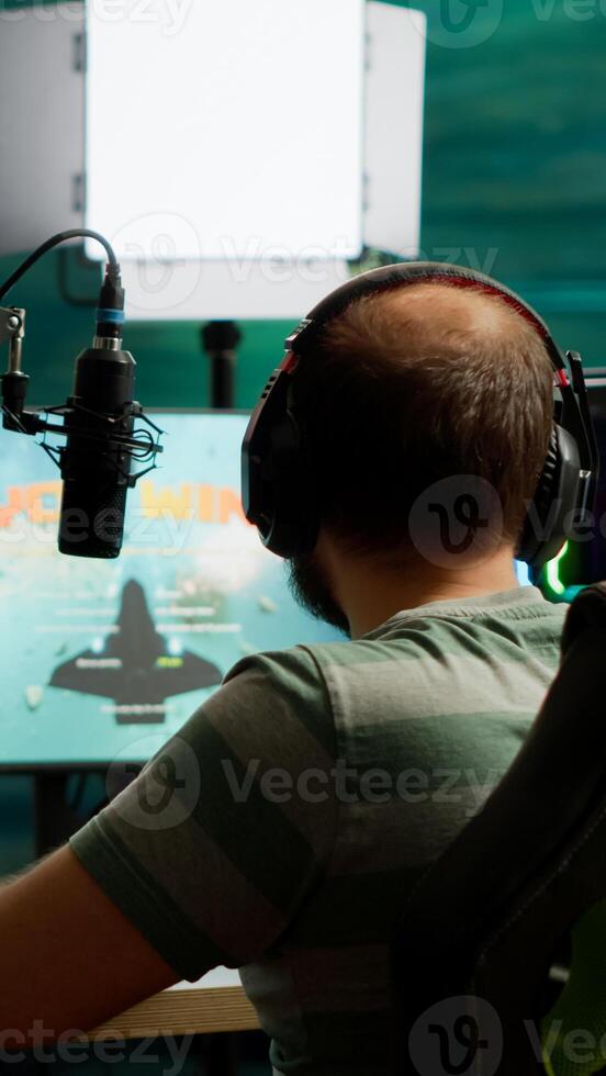 Professional streamer winning space shooter videogame at live competition playing from home studio. Online streaming cyber performing during gaming tournament using powerful computer with RGB lights photo