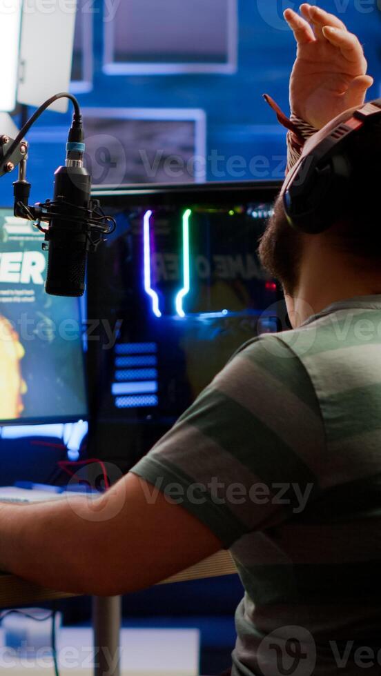 Videogame streamer losing online videogame competition wearing professional headset talking on stream chat. Sad gamer using powerful computer for gaming tournament late night playing space shooter game photo
